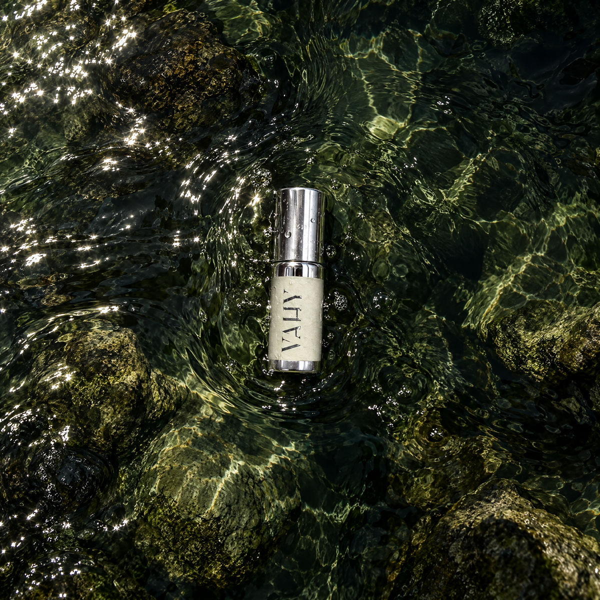 R-OIL 5ml natural perfume oil in clear water over mossy rocks